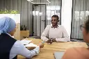 man-sitting-down-office-job-interview-desk-with-his-employers.webp
